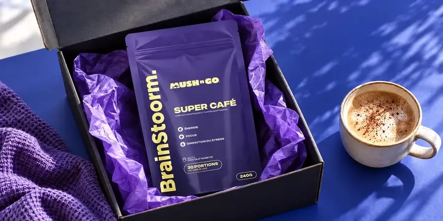 Busta di Brainstoorm appena arrivata in una scatola nera aperta con carta velina viola, accanto a una tazza schiumosa su fondo blu