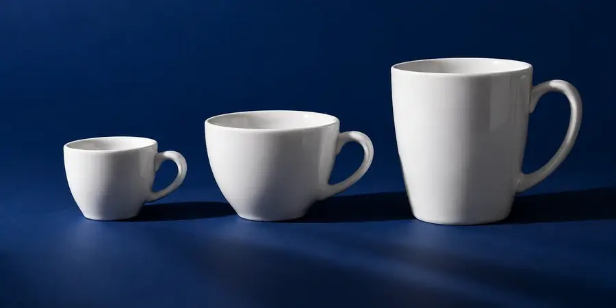 Tre tazze di misure diverse, da una tazzina da espresso a una tazza grande, allineate su fondo blu notte