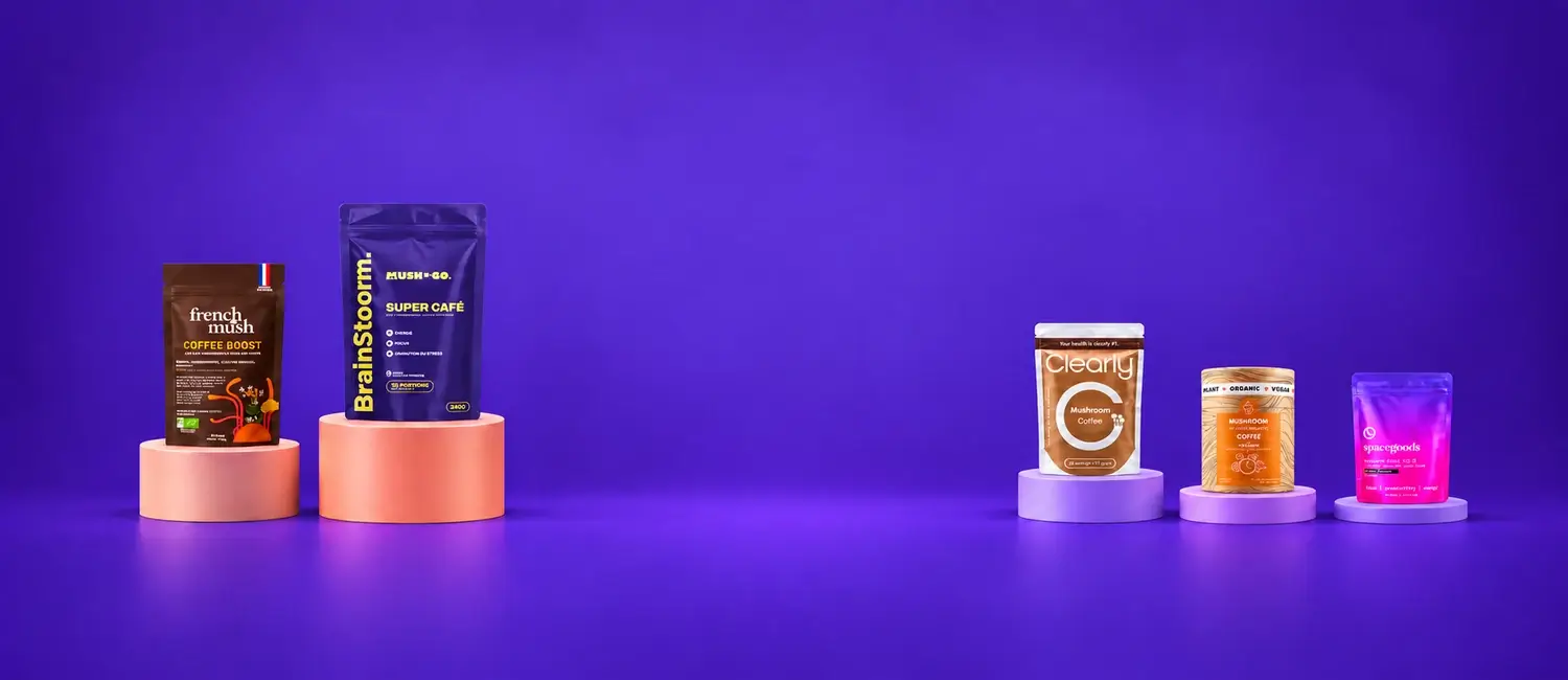 Le confezioni di Brainstoorm, French Mush Boost Caffè, Clearly Mushroom Coffee, Go Sharp e Rainbow Dust su podi rotondi di altezze diverse, davanti a un fondo viola acceso